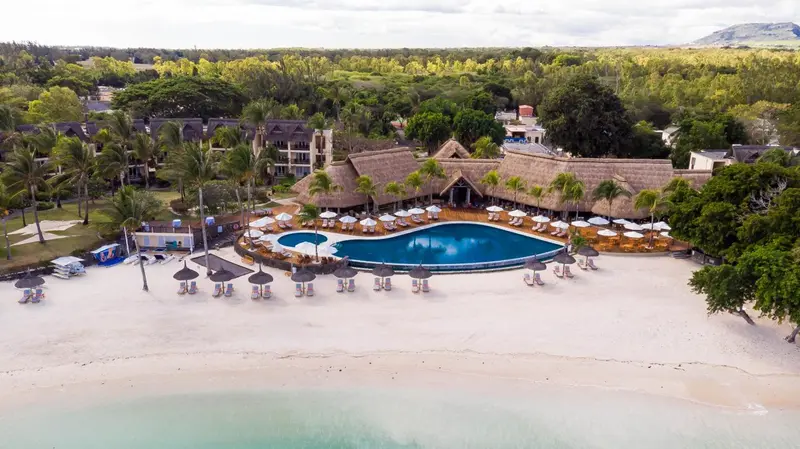 Vue aérienne d'un complexe hôtelier avec piscine et plage de sable blanc.