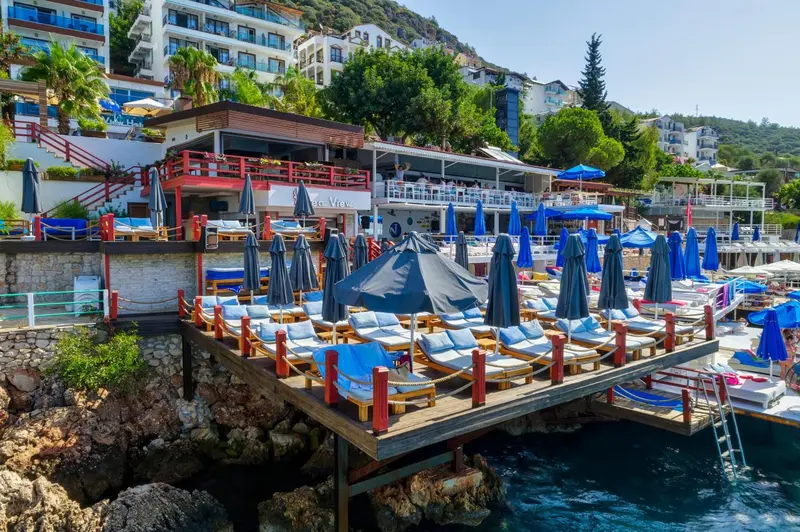 Terrasse en bois avec transats et parasols au bord de la mer.