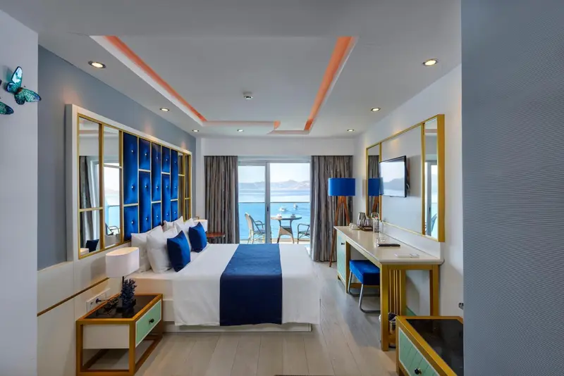 Chambre moderne avec un grand lit et vue sur la mer.