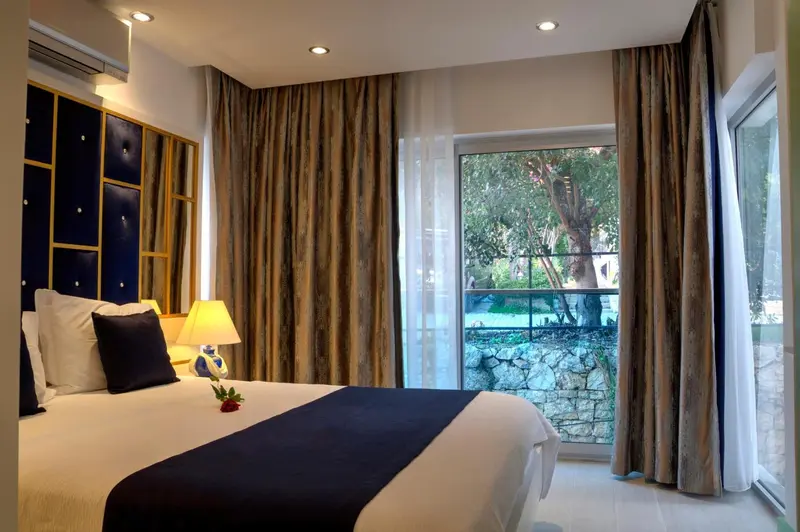 Une chambre lumineuse avec un grand lit et un accès à une vue extérieure.