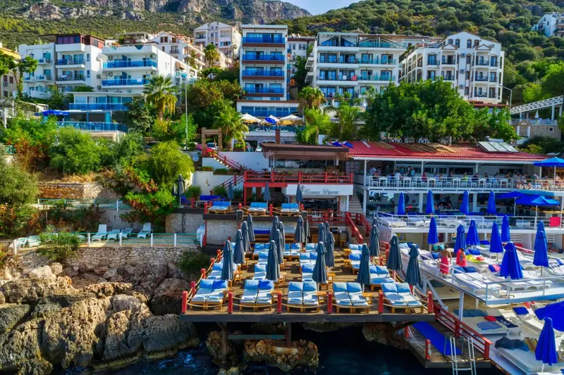 Vue d'ensemble d'un complexe hôtelier en bord de mer avec des transats et des parasols.