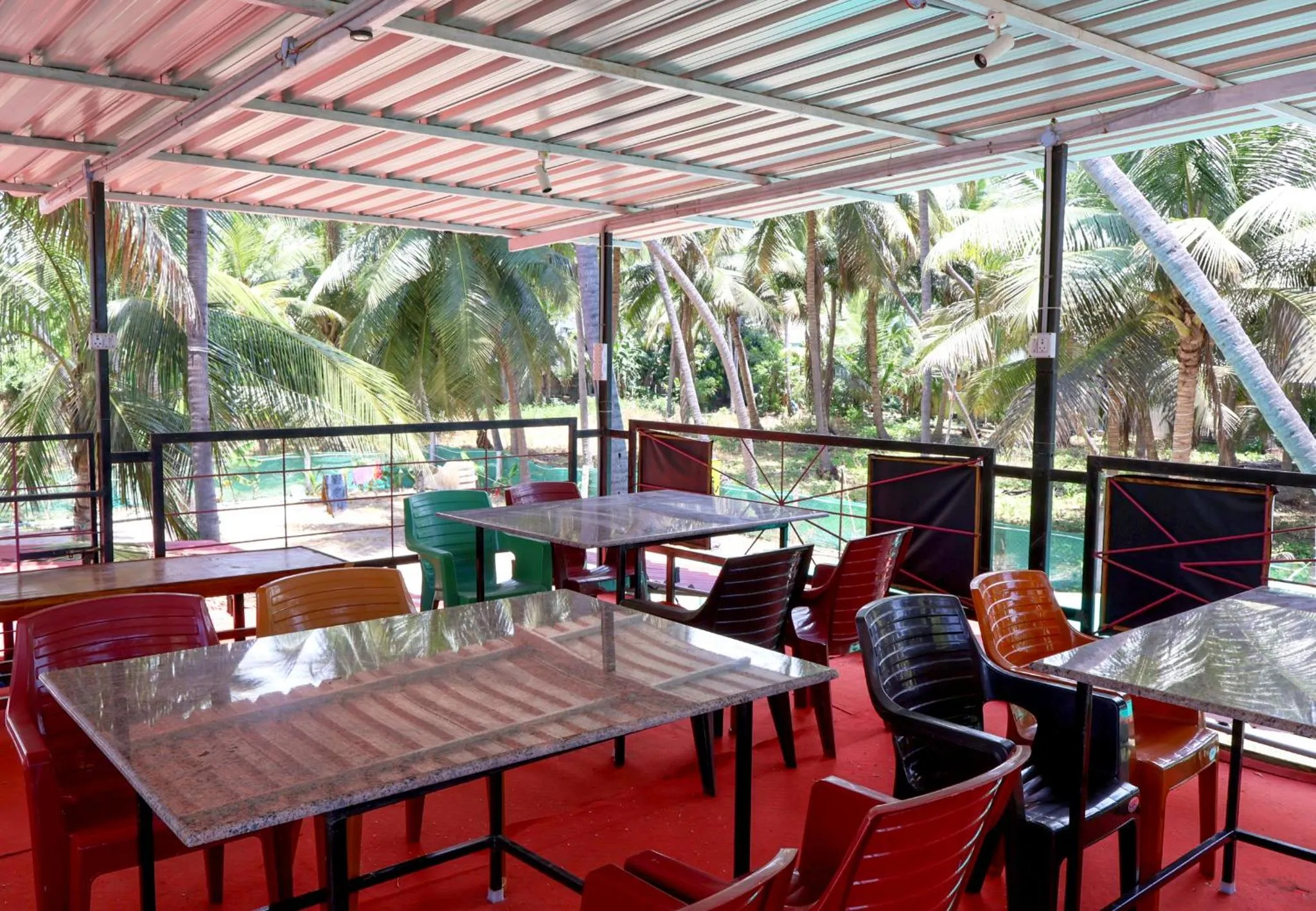 Terrasse ombragée avec tables et chaises colorées.