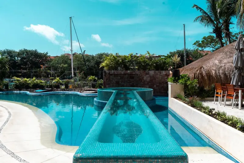 Piscine avec toboggan et mobilier de jardin.