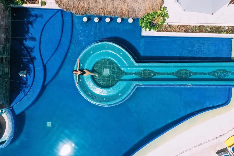 Vue aérienne d'une piscine avec toboggan et une personne allongée dans l'eau.
