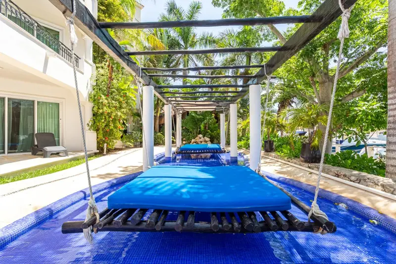 Bains de soleil sur des lits d'eau bleus sous une pergola ombragée.