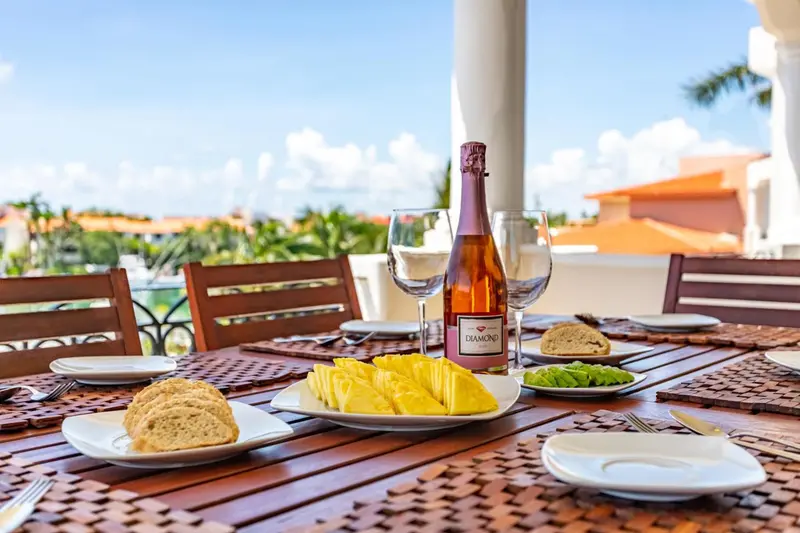 Une table est dressée avec des fruits, des viennoiseries et une bouteille de boisson.