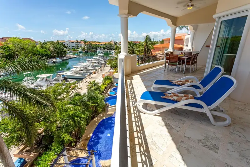 Terrasse avec mobilier de relaxation donnant sur un port de plaisance.