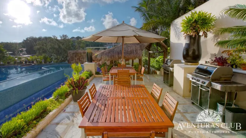 Terrasse aménagée avec mobilier de jardin et barbecue près d'une piscine.