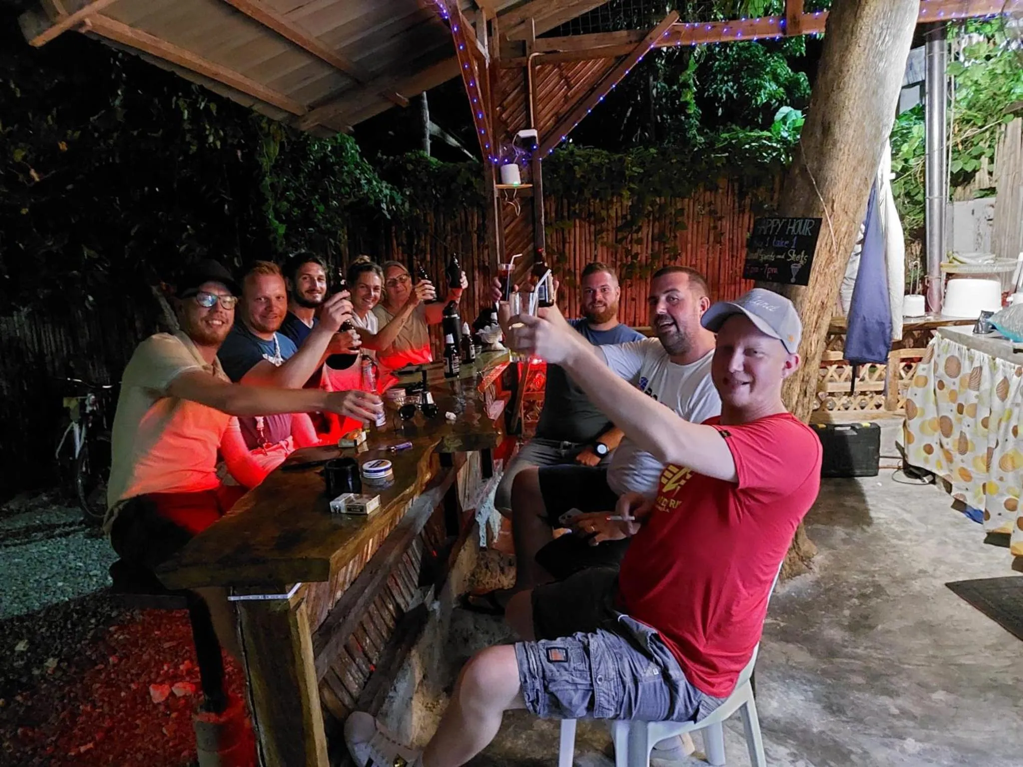 Un groupe de personnes lève ses verres dans un bar en plein air.
