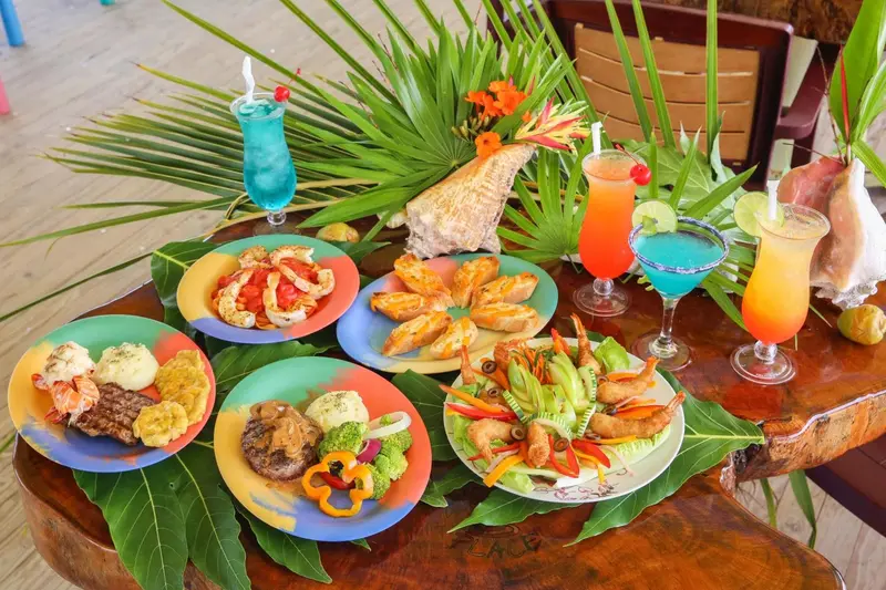 Une table colorée présente une variété de plats exotiques et de boissons tropicales.