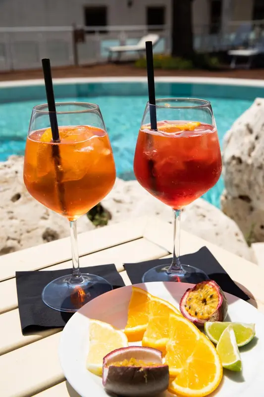 Deux verres de cocktail colorés sur une table basse près d'une piscine.