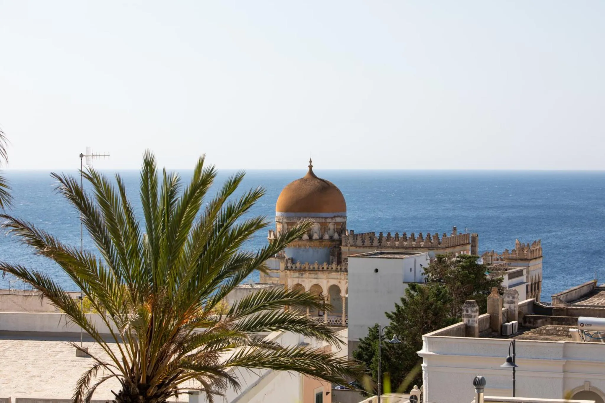 Vue d'une architecture beige et blanche surplombant la mer bleue.