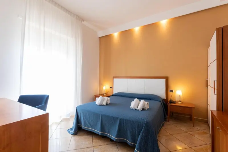 Une chambre lumineuse avec un grand lit recouvert d'une couverture bleue.