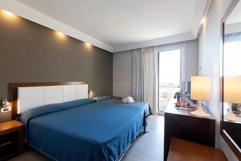 Une chambre lumineuse avec un grand lit et un accès à un balcon.