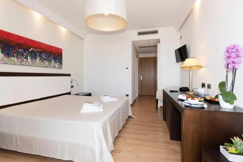 Chambre lumineuse avec un grand lit et une décoration florale.