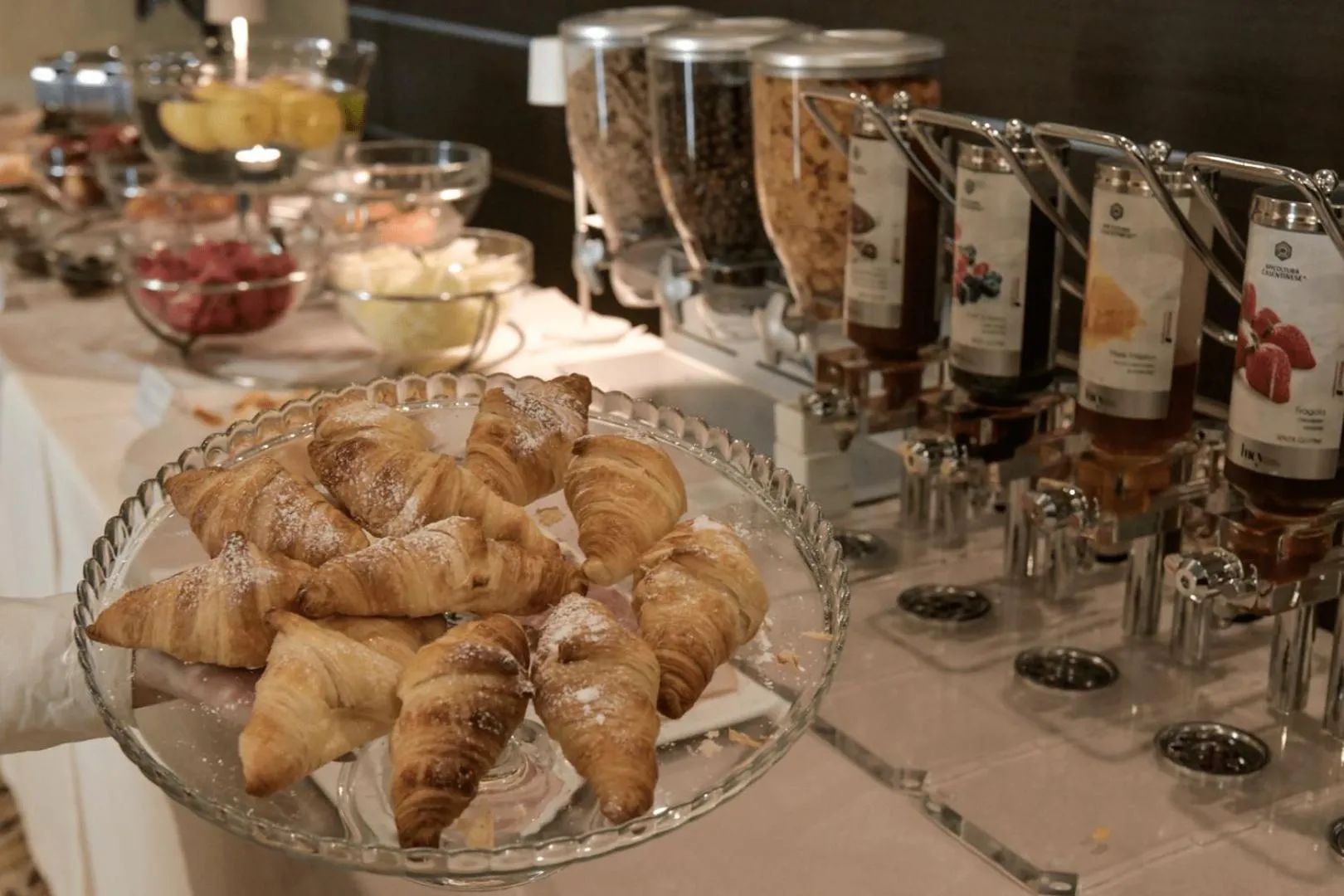 Une présentation de viennoiseries et de confitures sur un buffet.