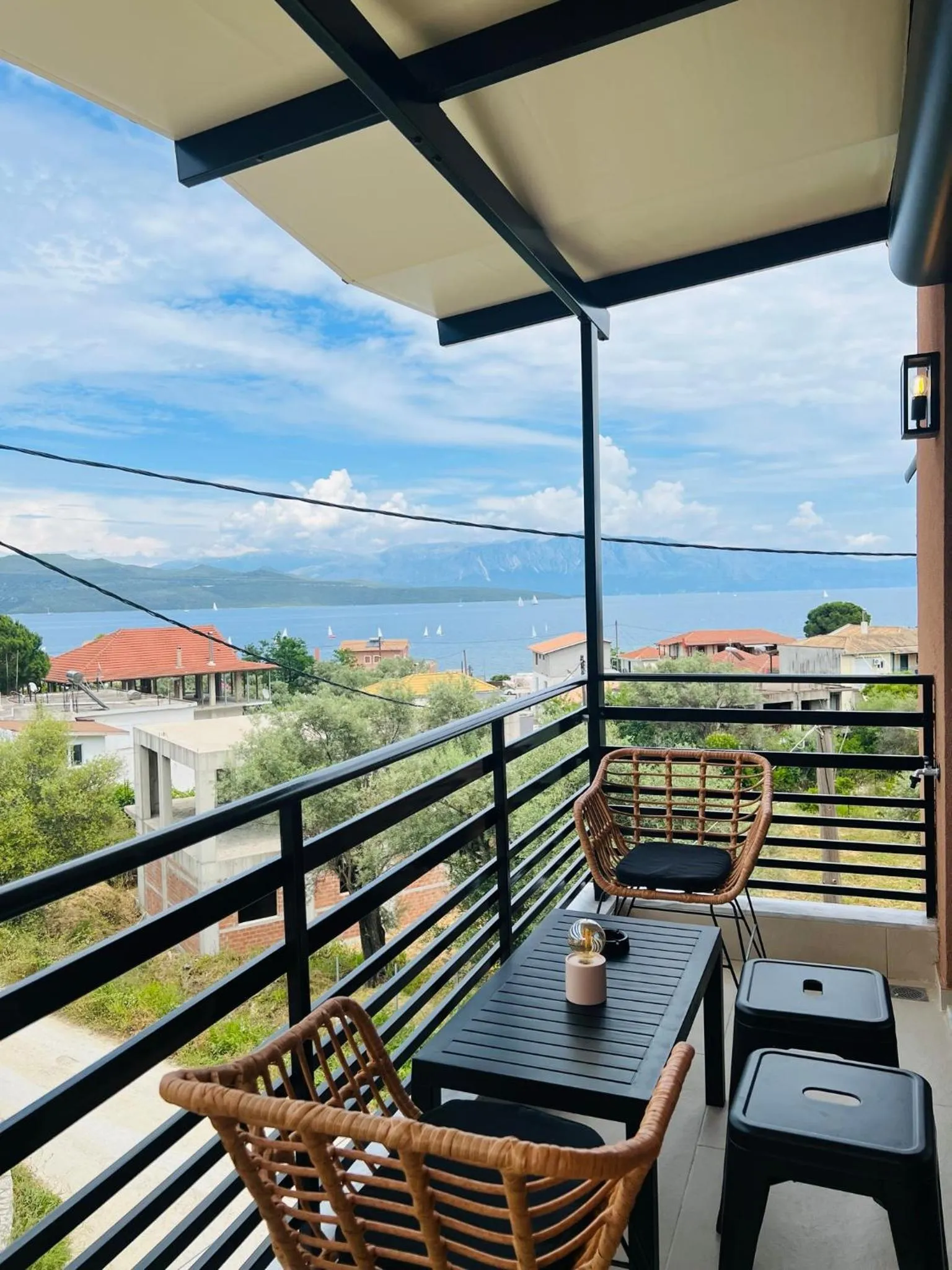 Terrasse avec mobilier en rotin donnant sur une vue mer et des bâtiments.