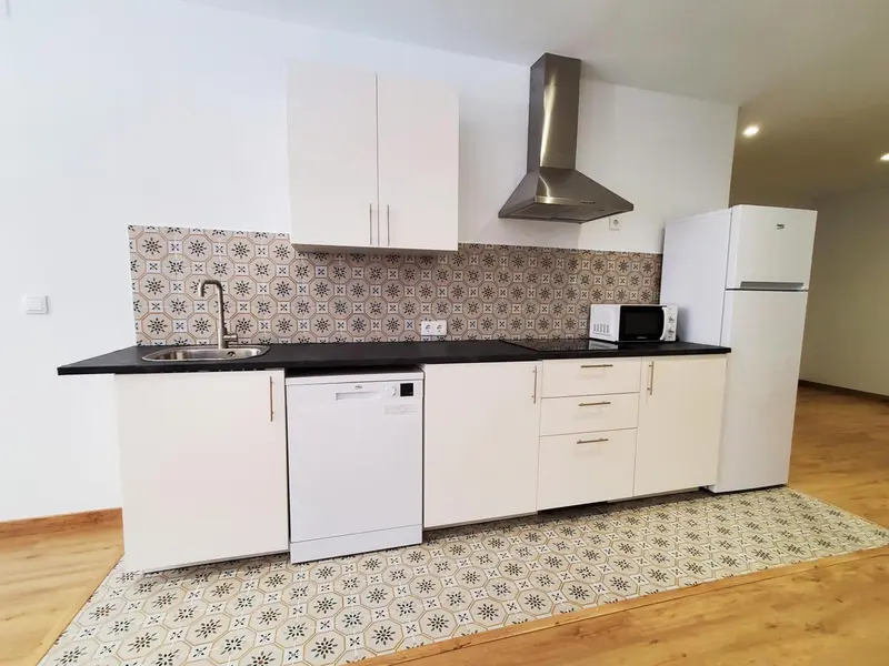Cuisine moderne avec plan de travail noir et carrelage décoratif.