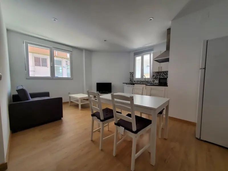 Une pièce lumineuse combine un espace repas avec une cuisine équipée et un coin salon.