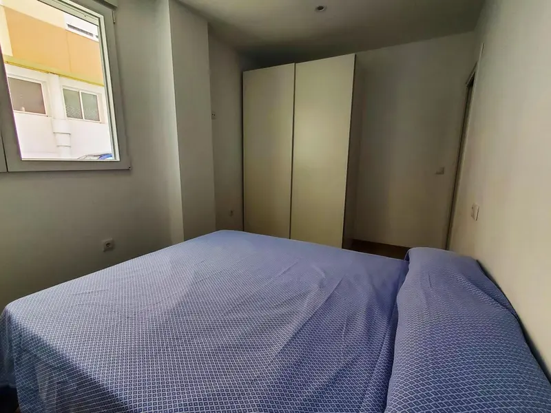 Une chambre avec un lit recouvert d'une couverture bleue et un grand placard.