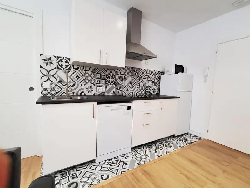 Cuisine moderne avec carrelage décoratif et électroménager blanc.
