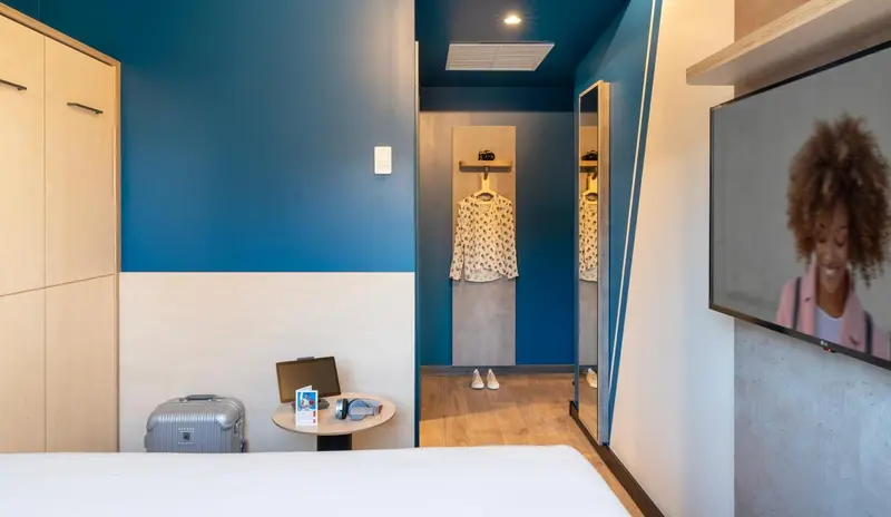 Une chambre moderne avec un lit blanc et un téléviseur mural.