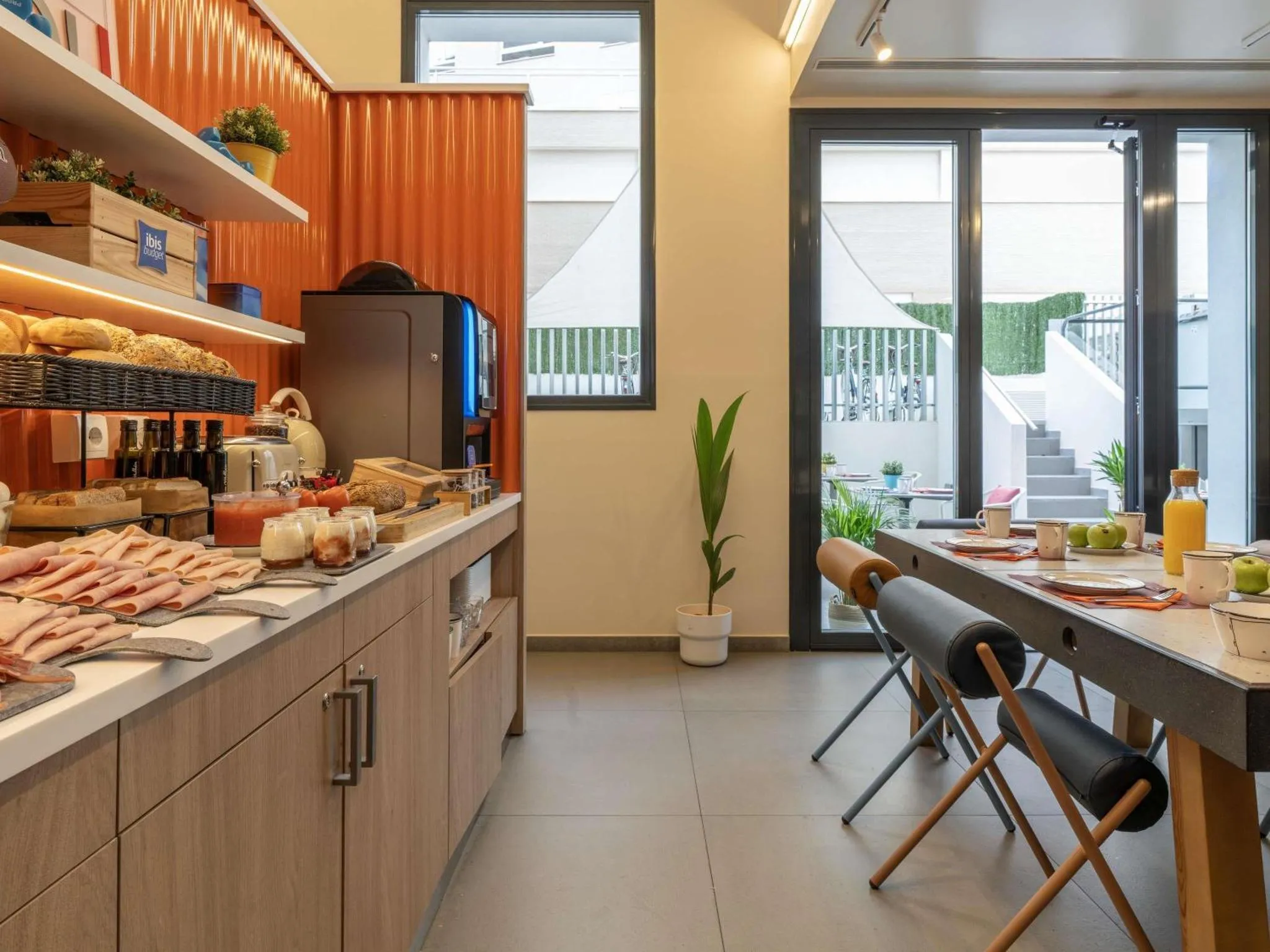 Un comptoir de buffet propose des viennoiseries, des fruits et des boissons dans une salle lumineuse.