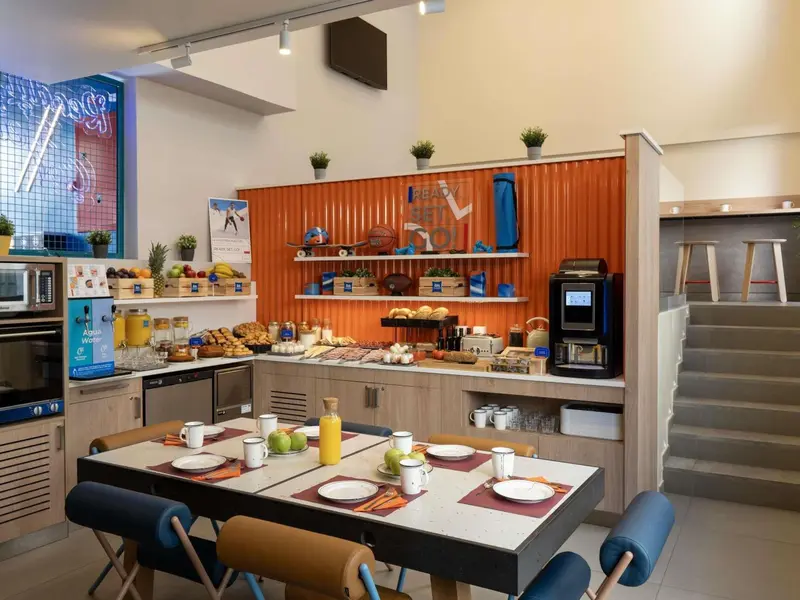Une table est dressée pour le petit-déjeuner avec des viennoiseries et des jus de fruits.
