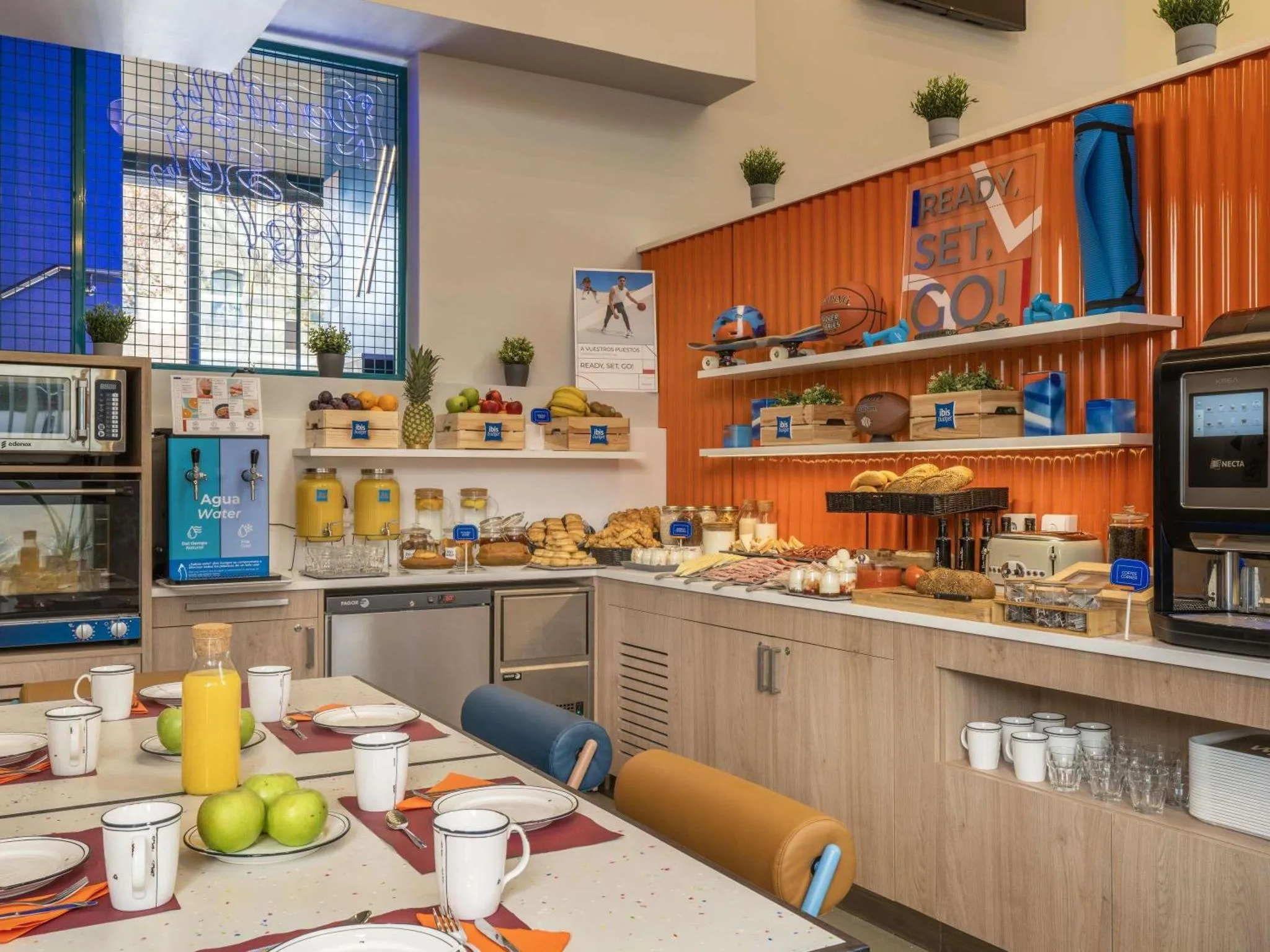 Une table est dressée avec des couverts, des assiettes de fruits et des boissons.