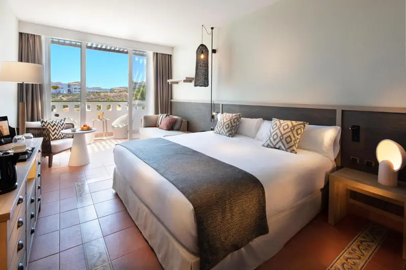Une chambre lumineuse avec un grand lit et un coin salon.