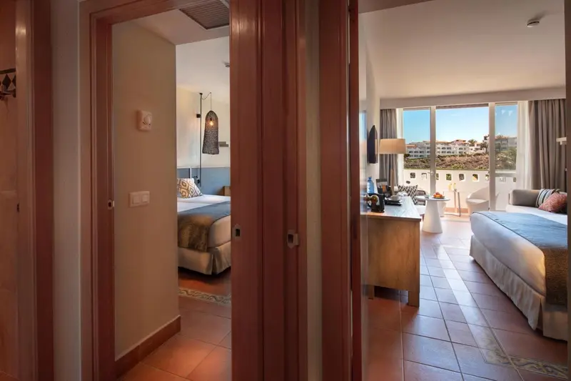 Une chambre lumineuse s'ouvre sur un espace de vie avec canapé et balcon.