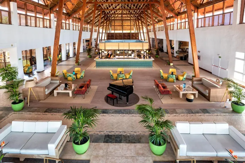 Vaste espace de réception lumineux avec mobilier contemporain et plantes tropicales.