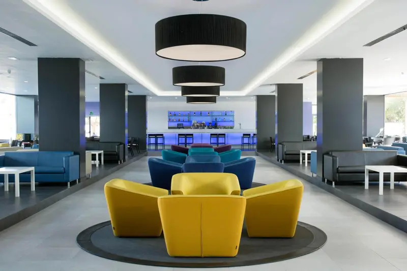 Espace de détente intérieur avec canapés colorés et bar lumineux.