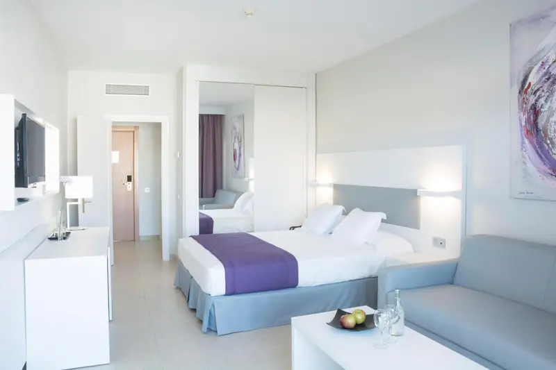 Chambre lumineuse avec un lit double et un espace détente.