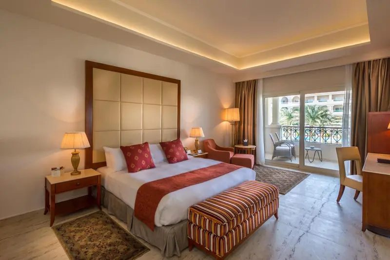 Une chambre lumineuse avec un grand lit et un coin salon.