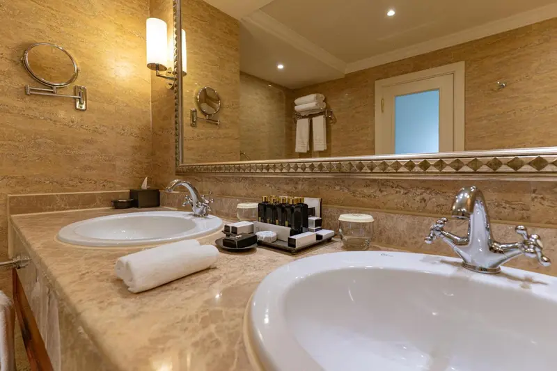 Une salle de bain lumineuse avec deux vasques et des miroirs.