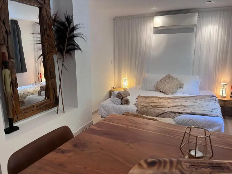 Une chambre lumineuse avec un grand lit et une table en bois au premier plan.