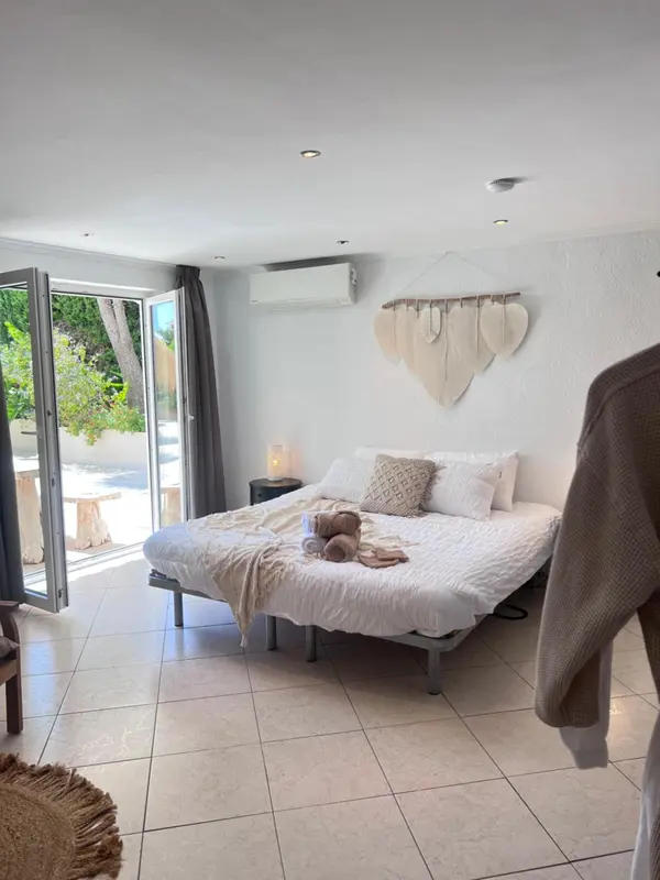 Une chambre lumineuse avec un grand lit et un accès à une terrasse.