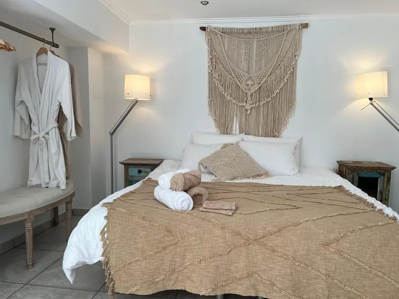 Une chambre lumineuse avec un grand lit recouvert d'une couverture texturée et décorée d'oreillers.