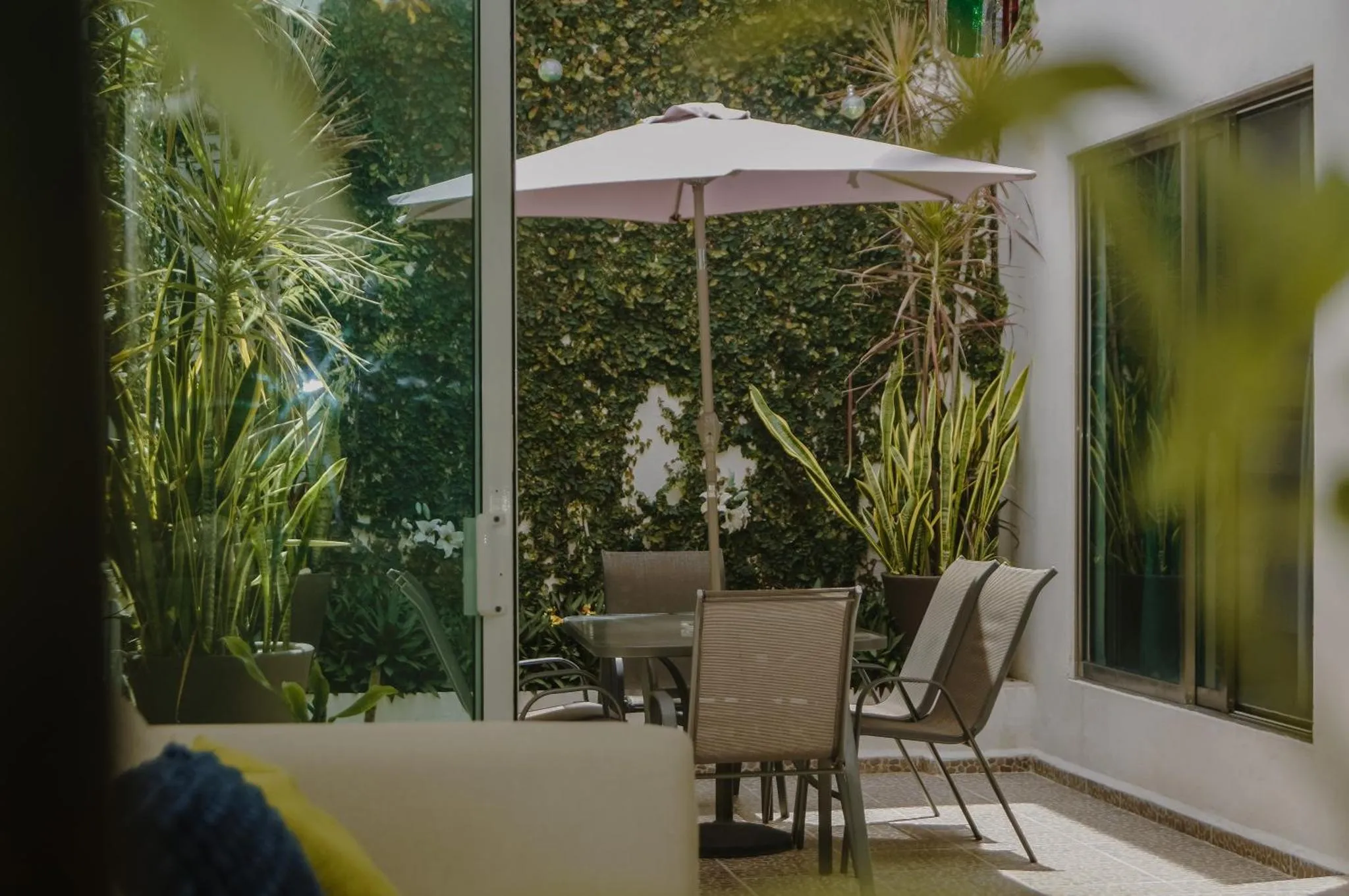 Une table et des chaises se trouvent sur une terrasse ombragée par un parasol.