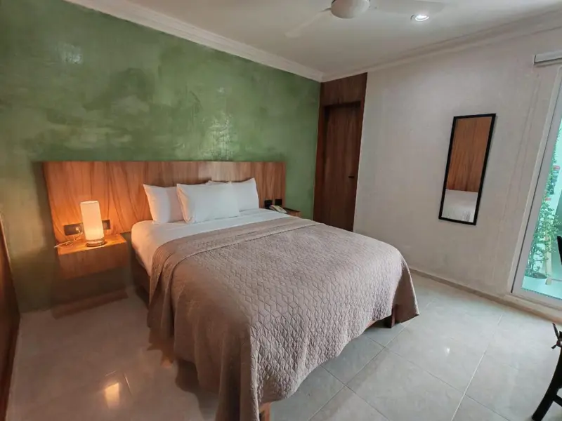 Une chambre lumineuse avec un grand lit recouvert d'une courtepointe.