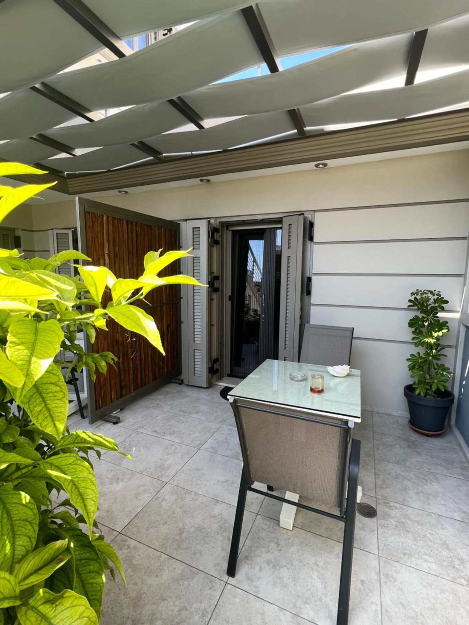 Terrasse ombragée avec table et chaises.