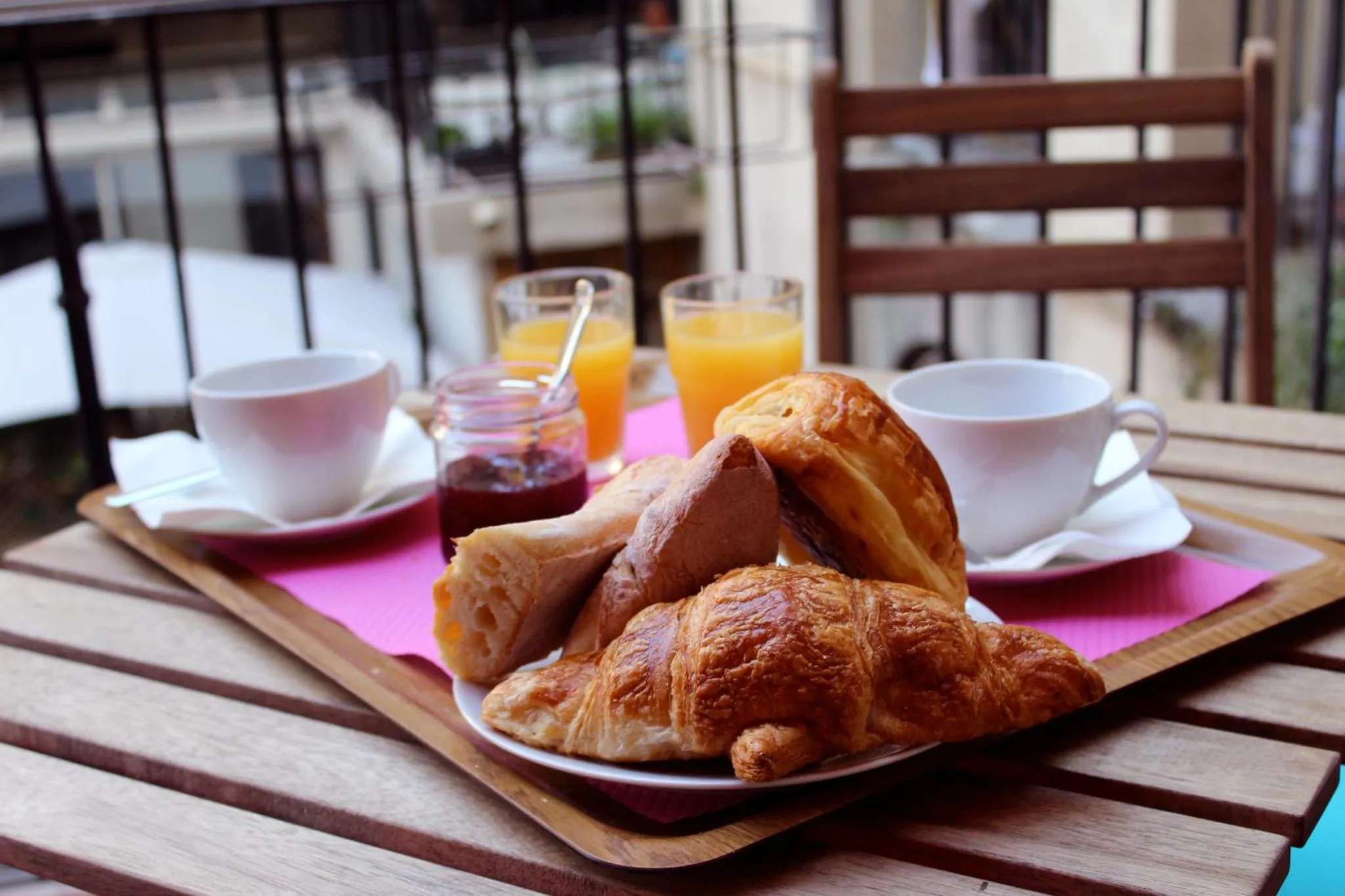 Un petit-déjeuner avec des viennoiseries et des jus d'orange est servi sur une table en bois.