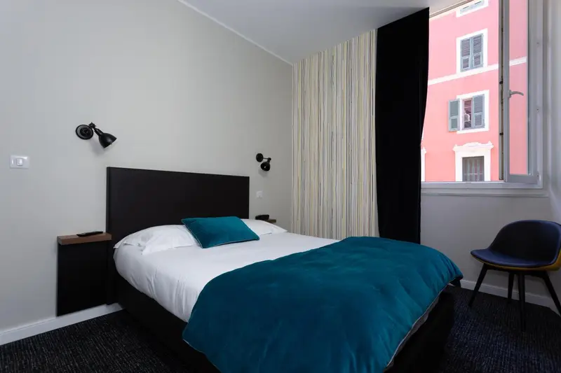Une chambre avec un lit recouvert d'une couette turquoise et une chaise.