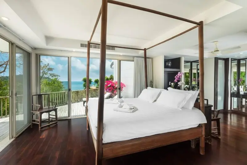 Une chambre spacieuse avec un lit à baldaquin donnant sur une vue mer.