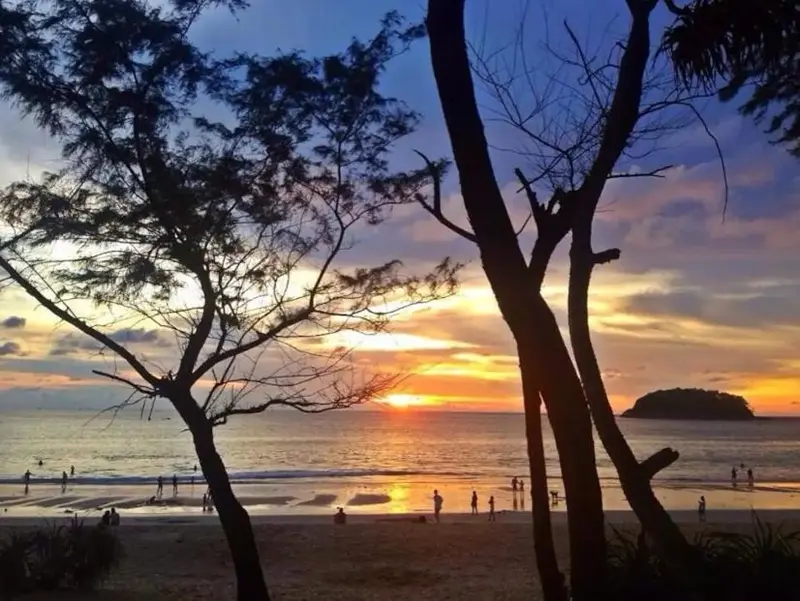 Coucher de soleil sur une plage avec des silhouettes de personnes.