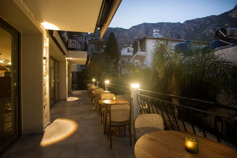 Terrasse lumineuse avec tables et chaises devant un bâtiment.