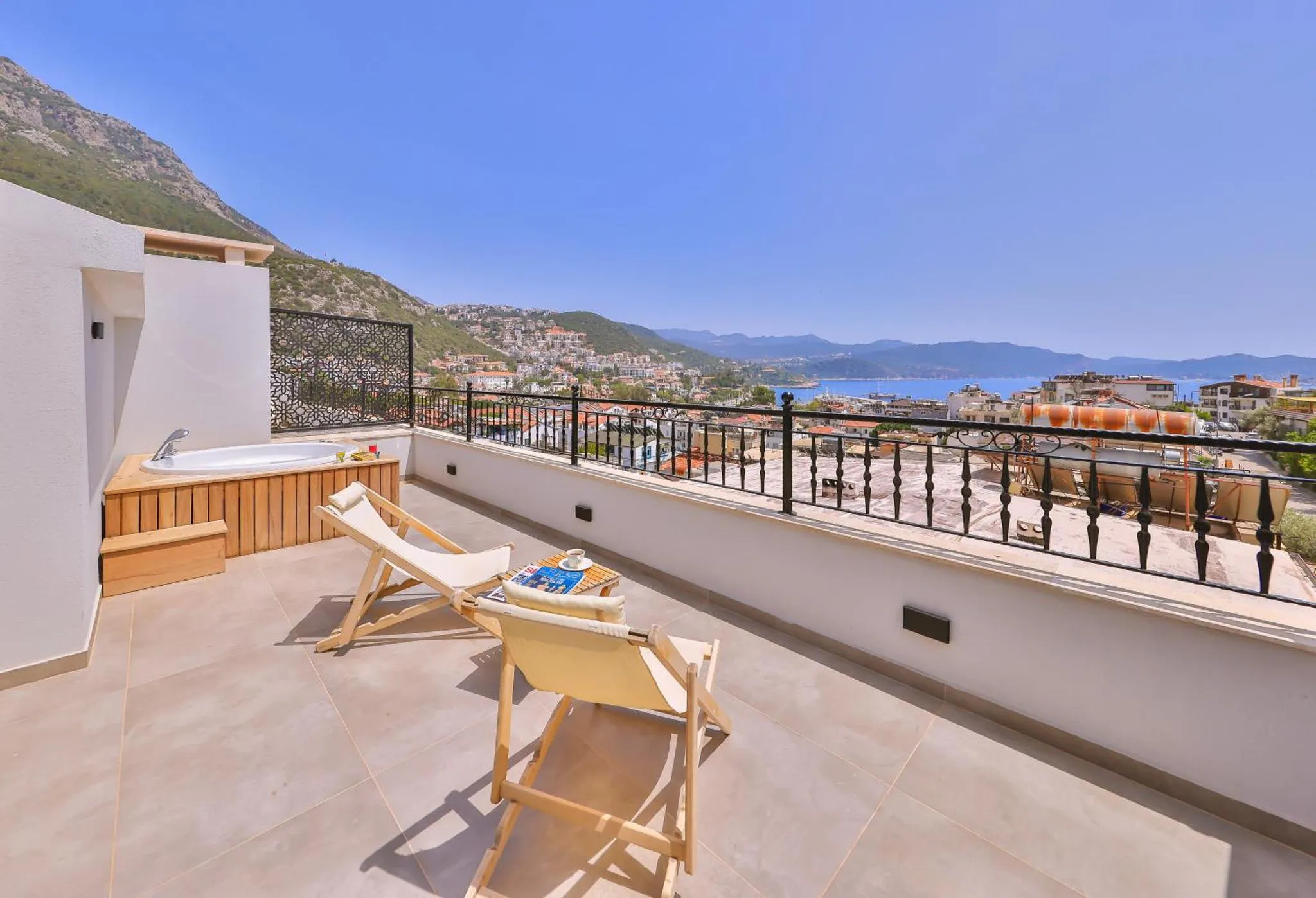 Terrasse avec jacuzzi et mobilier de jardin offrant une vue sur la mer et la ville.