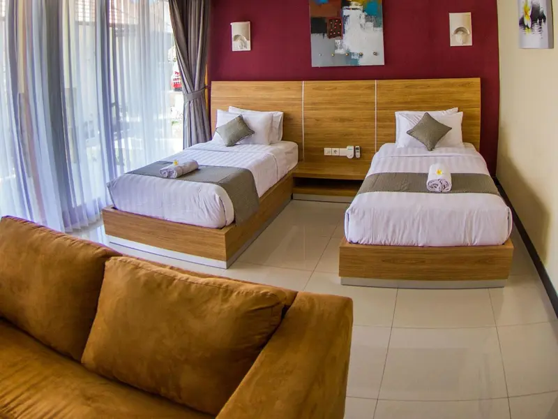 Deux lits simples avec oreillers et couvertures dans une chambre décorée de couleurs chaudes.