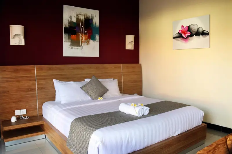 Une chambre lumineuse avec un grand lit et des tableaux décoratifs.